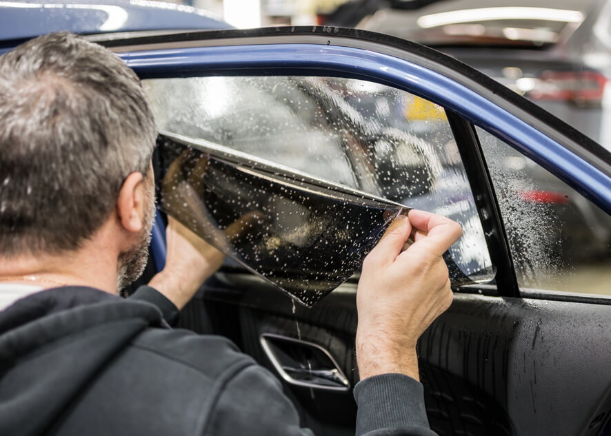 Car rear window being tinted using dark UV protection film