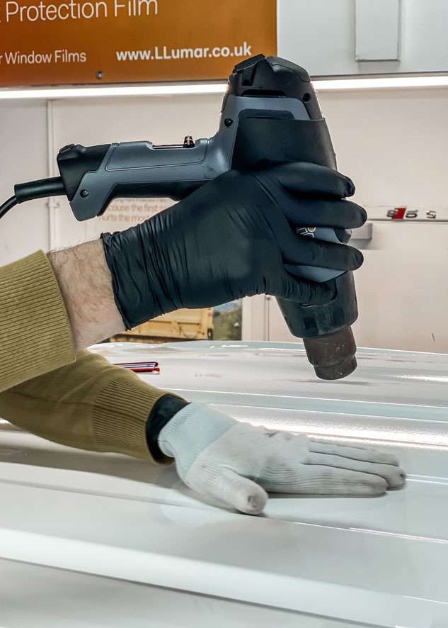Blue Land Rover Defender roof being vinyl wrapped in white