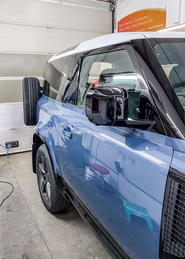 Blue Land Rover Defender with vinyl wrapped white roof
