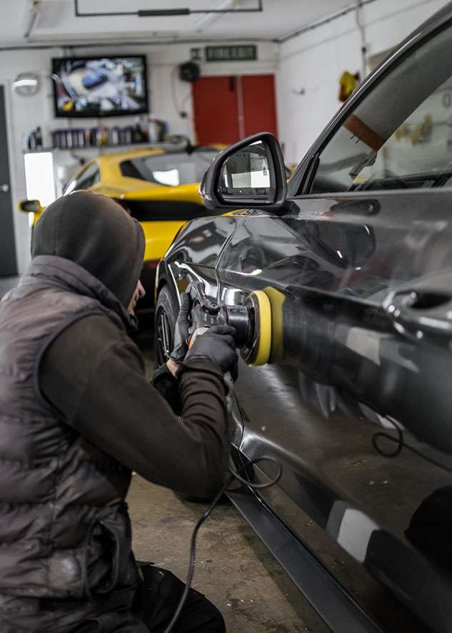 Man in gloves polishing Grey Mustang GT with machine