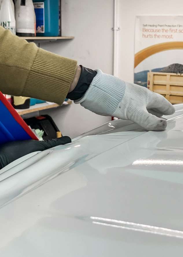 Blue Land Rover Defender roof being vinyl wrapped in white