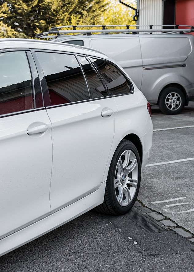 Rear side shot of white BMW 5 series with tinted windows
